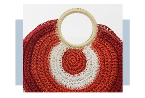 Detail view of red and white striped straw bag showing woven texture and round handles