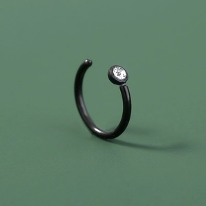 Black stainless steel U-shaped nose ring with a clear zircon stone on green background
