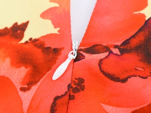 Detailansicht des weißen Reißverschlusses am eleganten rot-gelben Blumen-Maxikleid