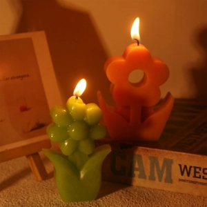 Detalle de velas aromáticas florales en naranja y verde con pétalos realistas