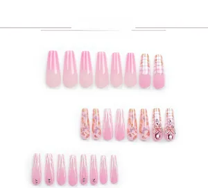 Detail of pink coffin press-on nails with gold butterfly charms and rhinestone accents
