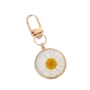 Golden keychain featuring a real white daisy flower preserved in clear resin charm