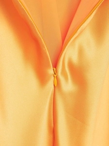 Détail de la fermeture éclair invisible sur une robe mi-longue en satin orange