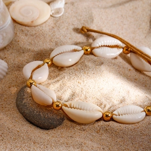 Bracelet de cheville bohème avec coquillages naturels et perles dorées sur sable
