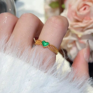 Detail of a 24k gold floral ring with a green heart and hollow trapezoidal band