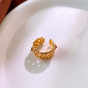 Detailed macro view of gold-plated textured ring with sparkling zircon star accents