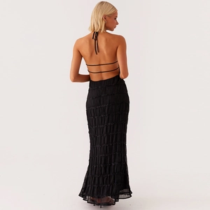 Detail of black backless maxi dress featuring tiered pleats and halter neck ties