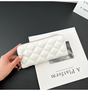 Detail of elegant white quilted patent leather clutch purse with luxury gold zipper