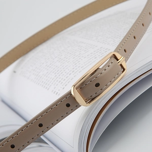 Close-up of light brown leather belt with gold metal buckle and white stitching detail