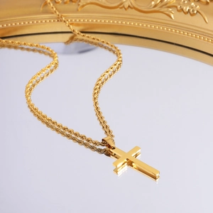 Macro detail of gold cross pendant with twisted rope chain on a vintage mirror surface