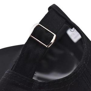Detailed view of the adjustable silver metal buckle on the black cotton baseball cap