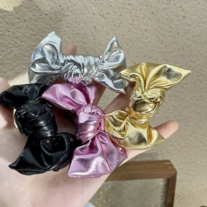 Close-up of four glittery bow hair clips in silver, gold, pink, and black colors