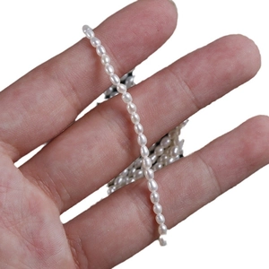 Strand of high-luster 2.5mm natural freshwater seed pearls held for size scale