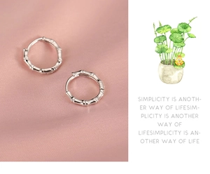 Close-up of silver bamboo hoop earrings on pink silk fabric with minimalist design