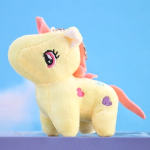 Close-up of yellow plush unicorn keychain with pink mane and embroidered hearts