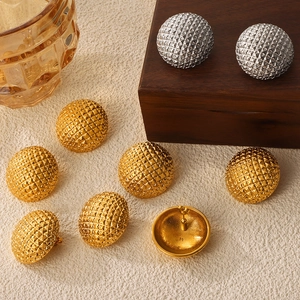 Vintage round gold and silver earrings with embossed diamond pattern on wood display