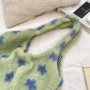 Detail of green faux shearling tote bag featuring floral patterns and gingham lining