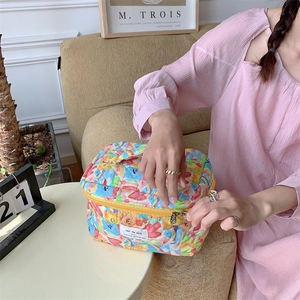 Trousse de toilette en coton matelassé à fleurs avec poignée sur un canapé douillet