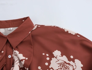 Détail d'une chemise florale rouge-brun avec col à revers, boutons et étiquette S