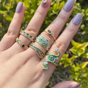 Close-up of green heart and snake rings with gold finish and zircon details on fingers