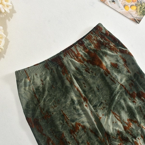 Dettaglio ravvicinato del tessuto tie-dye verde e marrone sui leggings dal taglio slim