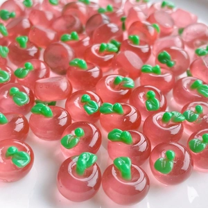 Macro shot of miniature red resin apples with green leaves for DIY crafts and decor