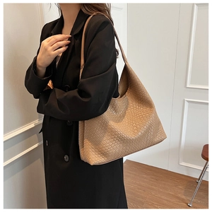 Khaki woven leather shoulder bag showing large capacity and fine texture on model