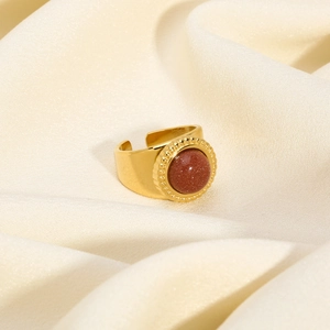 Detailed view of an adjustable gold ring with a round brown gemstone on silk