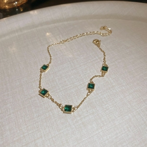 Gros plan détaillé du bracelet plaqué or orné de cinq pierres carrées vert émeraude