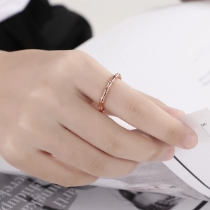 Detail of rose gold bamboo joint ring on finger with soft lighting background