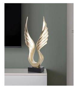 Detail of modern abstract golden wings sculpture on a black base for home decor