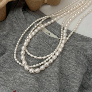 Multilayer freshwater pearl necklace with rice-shaped beads on a casual grey shirt