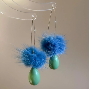 Dettaglio macro di eleganti pompon blu e perle a goccia verdi su ganci in argento