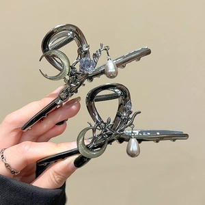 Detail of dark metal hair claws with moon stones, metal flowers and pearl pendants