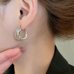 Close-up of double-layer intertwined silver hoop earrings with shimmering pavé diamonds