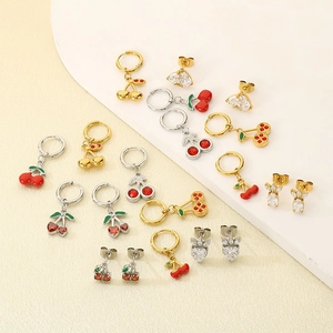 Flat lay detail of strawberry and cherry fruit earrings with zircon and red enamel