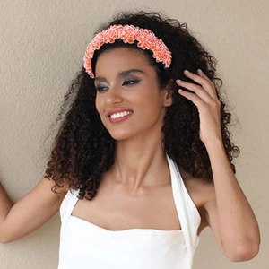 Detail view of a handmade orange fabric flower headband worn by a stylish model