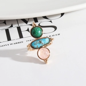 Detail of bohemian gold ring set with green, blue, and pink natural stones on ceramic tray