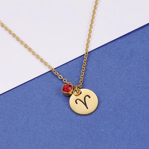 Golden Aries zodiac necklace with a round cutout pendant and a sparkling red gemstone