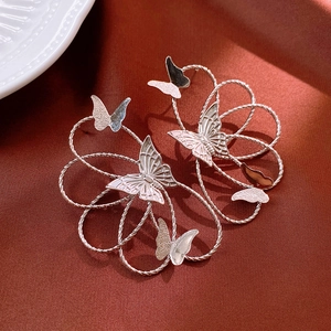 Detail of silver twisted metal flower wreath earrings with butterfly accents on satin