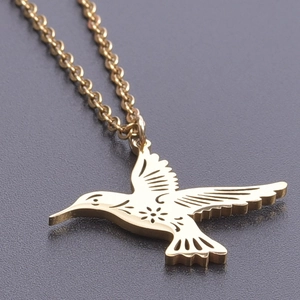 Detailed close-up of a gold hummingbird pendant with intricate floral engravings and link chain