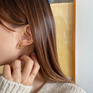 Minimalist 925 sterling silver hoop earrings and rings worn by a model in soft golden light