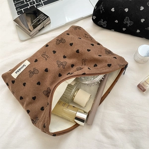 Dettaglio di una trousse in velluto a coste marrone con fiocchi e cosmetici interni