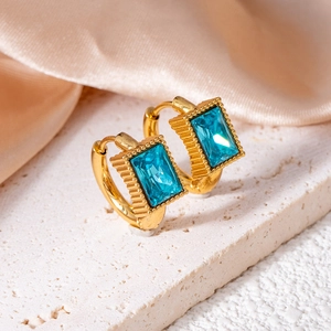 Detailed close-up of gold star earrings with rectangular blue crystals on silk