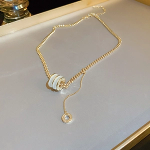 Macro detail of golden cylindrical pendant with white ceramic inlay and elegant chain