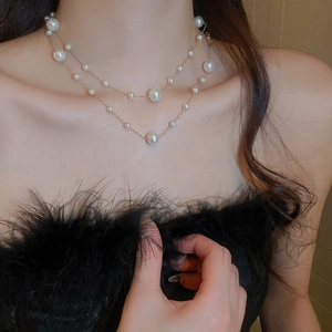 Detail of double-layer gold plated necklace with white pearls and beads on a model