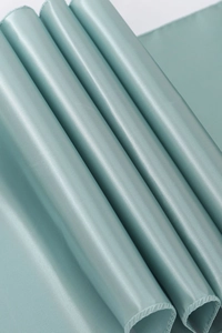 Macro shot of smooth light teal satin fabric with elegant drape and glossy texture