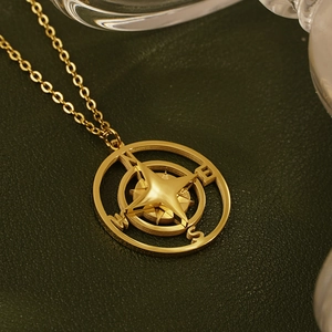 Vintage gold compass pendant necklace with N/E/S/W engraving on dark leather background