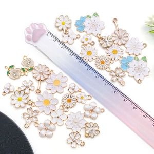Close-up of white flower charms and daisy pendants with gold trim for DIY jewelry