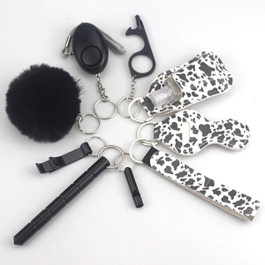Detail view of a cow print self-defense keychain set including alarm and accessories